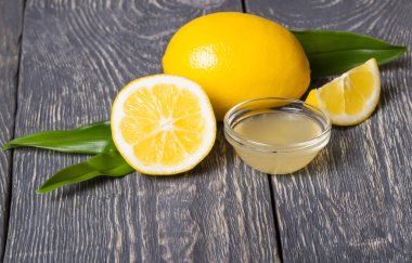 Lemon with leaves, Cup of lemon juice on wooden surface