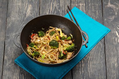 Spicy Asian dish in frying pan wok on table
