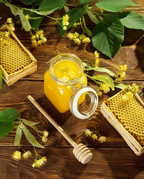 Frasco de mel de limão, armações com células de abelha, fuso e flores de tília na mesa — Fotografia de Stock