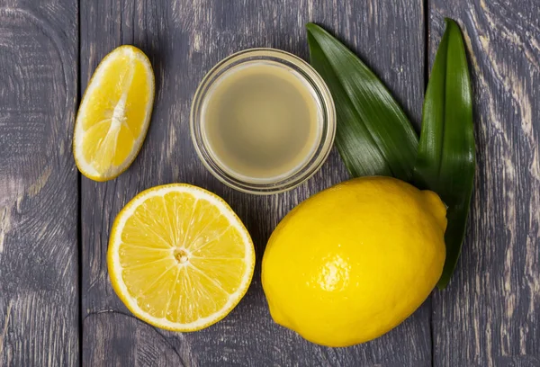 Piezas de limón y fruta, jugo en un tazón sobre una superficie de madera — Foto de Stock