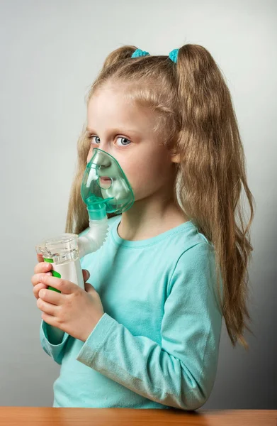 Nebulizador de malha com máscara nas mãos de menina no cinza — Fotografia de Stock