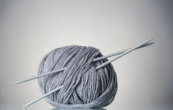 Coil of gray yarn and needles for needlework, on gray — Stock Photo, Image