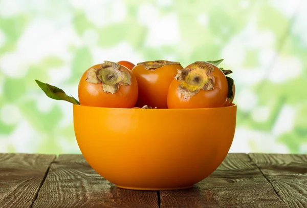 Full bowl of persimmon fruit on table — Stock fotografie