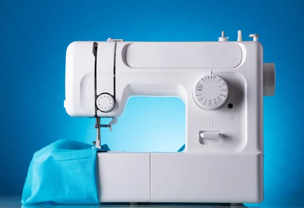 Sewing machine in work with fabric, on blue — Stock Photo, Image