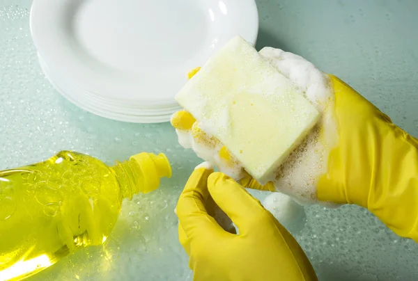 Maîtresse mains avec des gants laver la vaisselle sur la surface en verre de fond — Photo