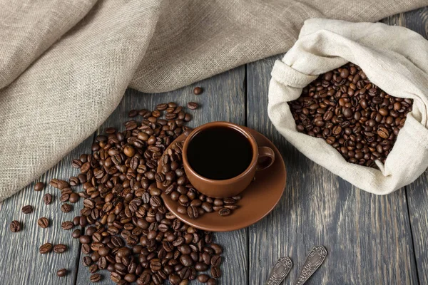 Tasse de café, sac de grains de café sur la surface en bois — Photo