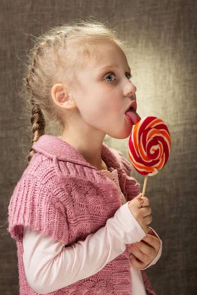 Девочка с детской спонтанностью ест конфеты на палочке — стоковое фото
