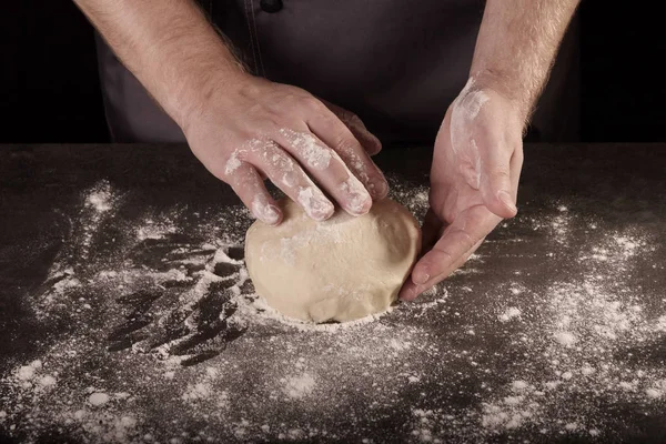 Руки Пекар замішує тісто на робочому столі, ізольовані на чорному — стокове фото