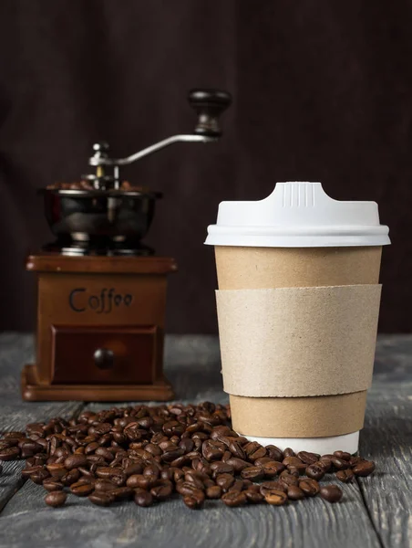 Special container for take-away coffee, beans of coffee and hand mill on table — Stok fotoğraf