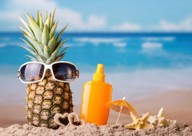 Ananas ve gözlük, kumdaki güneş kremi, denizyıldızı ve küçük kalpler.