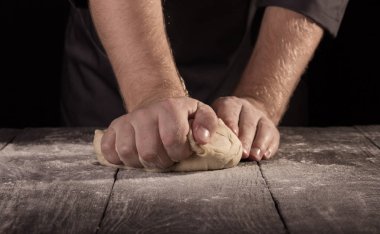 Baker 'ın elleri eski ahşap bir yüzeye un serpiştirilmiş hamuru yoğurdu.