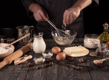 Baker 'ın elleri siyah arka planda izole edilmiş hamurla oynamak için bir malzeme ekler.