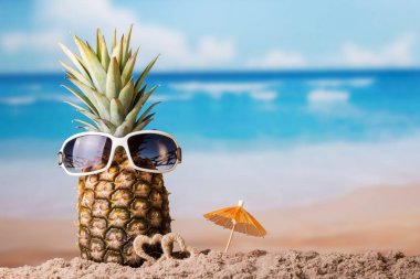 Gözlüklü ananas, küçük kalplerin yanında ve kumlu sahilde şemsiye.