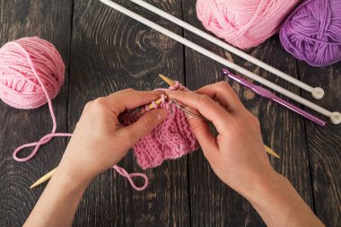 İplik, örgü aletleri, üstadın elinde hazır numune, koyu ahşap yüzeye karşı