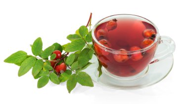 Fincanda gül kalçalarının ayrışması, çay tabağı, yapraklı dallar ve beyaz arka planda izole meyveler