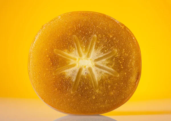 明るい黄色の背景に柿の断面 クローズアップ — ストック写真