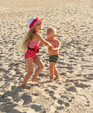 Küçük oğlan ve kız kumlu sahilde oynuyorlar