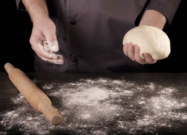 İş yüzeyinde un ve merdane, Baker 'ın elindeki hamur parçası, siyah arka planda izole edilmiş.