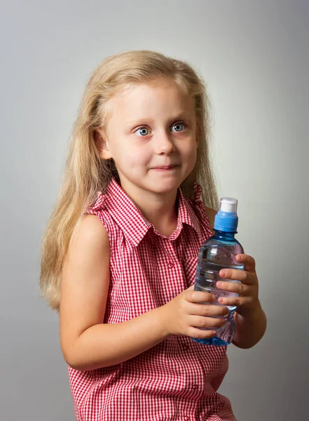 可愛いです小さな女の子とともに長い髪保持ボトルの水で灰色の背景 — ストック写真