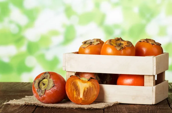 Cajón Lleno Caquis Naranjas Maduras Cerca Mitad Fruta Superficie Madera —  Fotos de Stock