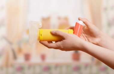 Portable nebulizer with child mask in female hand, on light background