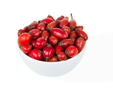 Beyaz arka planda izole edilmiş taze gül kalçalarıyla dolu seramik kase.