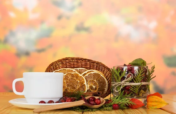 干橙片在篮子里 盛满玫瑰的碗里 茶托和勺子放在米色的木桌上 — 图库照片