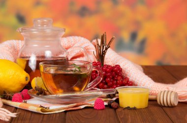 Bir sürahi çay, böğürtlen, meyve, soğuk algınlığı için bal, ahşap masada sıcak eşarp ve termometre.