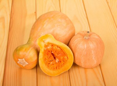 Büyük ve küçük balkabağı, dilimlenmiş sebze hamurlu ve tohumlu, bej ahşap masa üzerinde