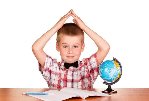 Chłopiec Siedzi Przy Stole Podnosząc Ręce Pobliżu Globu Notatnika Odizolowany — Zdjęcie stockowe