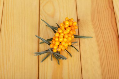 Hafif ahşap bir zemin üzerinde olgun deniz dikenli meyveler..