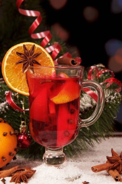 Karda, soyut koyu arka planda bir Noel ağacının yanında sıcak şarap..