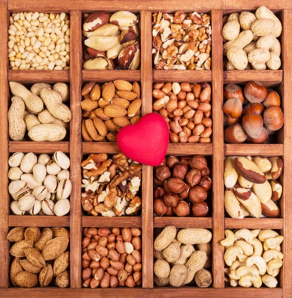 Whole, peeled nuts in a box, and in the middle of heart close up. Background.
