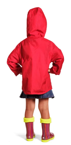 赤いジャケットの少女 青いスカートと白い背景に孤立立ってゴム製のブーツ バックビュー — ストック写真