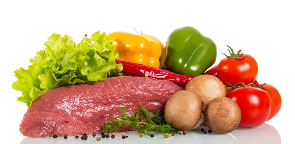 A piece of raw beef, vegetables, herbs and spices isolated on white background.