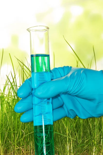 抽象的な緑の背景に肥料と手保持試験管 — ストック写真