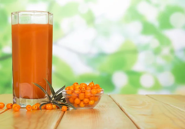 Een Glas Sap Een Kom Duindoornbessen Een Groene Abstracte Achtergrond — Stockfoto