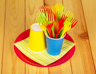 Parlak kağıt bardaklar, plastik çatallar ve arka planda hafif ahşap bir tabak..