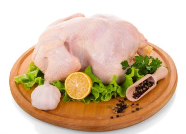 Beyaz arka planda çiğ tavuk eti, marul, limon, sarımsak ve biberli karatahta..