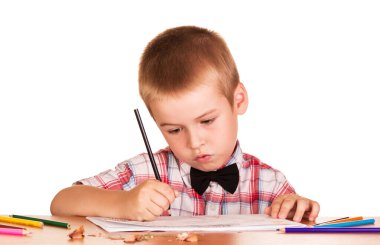 Çalışkan okul çocuğu masada oturuyor, beyaz arka planda izole bir şekilde çizim yapmak için albüm yapıyor..