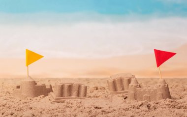 Denizin arka planında bayrakları olan kumdan kaleler.