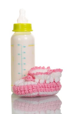 Beyaz arka planda izole edilmiş süt şişesi ve pembe botlar..
