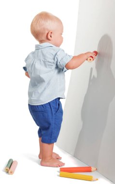 Küçük çocuk beyaz arka planda izole edilmiş büyük kırmızı bir kalem çiziyor..