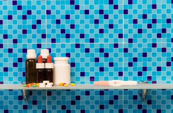 浴室里的架子 上面有怀孕测试 药物和药丸 背景是深蓝色的 — 图库照片