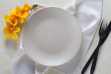 Masa örtüsü ve orkide çiçekli boş tabak ve peçete.