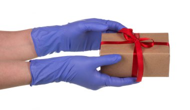 Mavi lateks eldivenli kadın elinde beyaz arka planda kırmızı bantlı kahverengi bir karton kutu var. Salgın sırasında güvenli ve çevrimiçi siparişler iletiliyor.