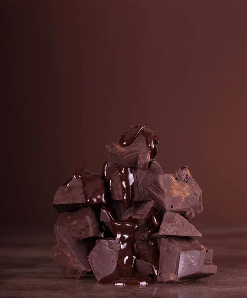 Kahverengi Arka Planda Erimiş Damlaları Olan Siyah Çikolata Parçaları Yakın — Stok fotoğraf
