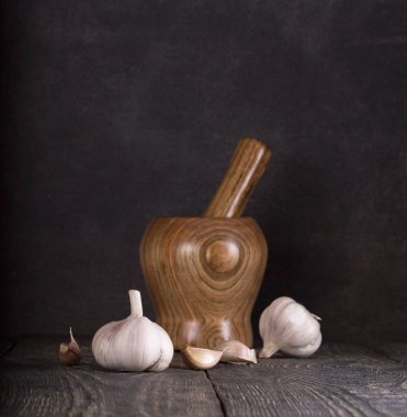 Koyu arkaplanda, ahşap bir masanın üzerinde taze sarımsak.