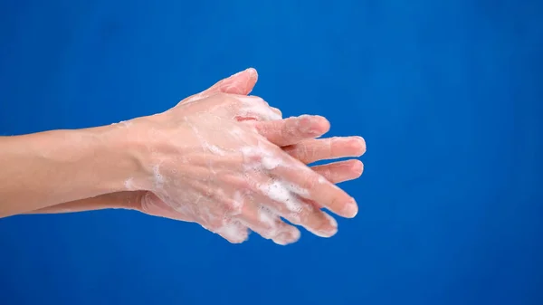 tutorial, woman wash hands with soap. closeup on blue background. protection against viruses and bacteria