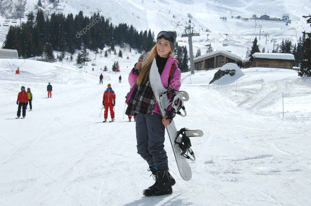 Woman snowboarder posing at the ski slope in Courchevel, France.